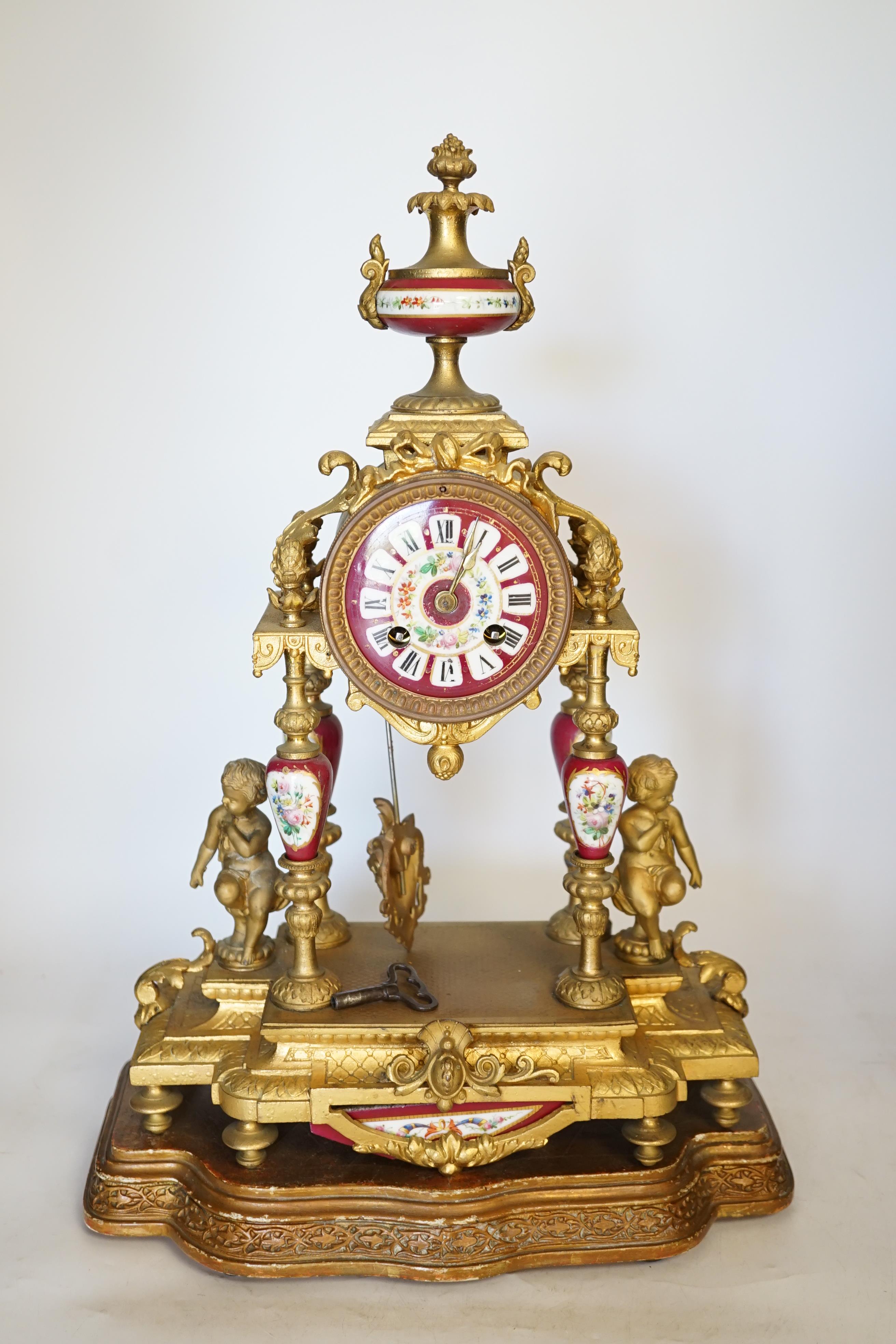 A late 19th century gilt metal and porcelain mounted mantel clock with associated stand, key and pendulum, 46cm. Condition - good to fair, not tested